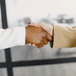 Close-up of a handshake between diverse business professionals indoors.